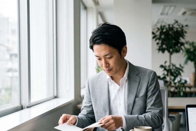 仕事前のオフィスで本を開き、習慣化に取り組むビジネスパーソン（行動経済学・行動科学）